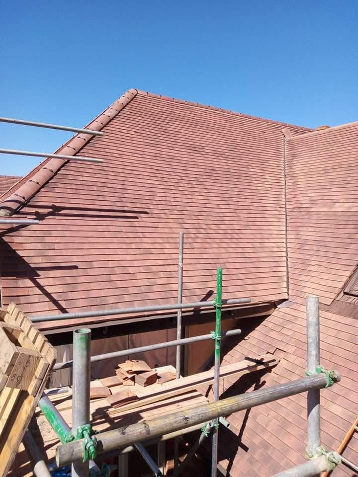 Steeply pitched red tiled roof under construction with scaffolding