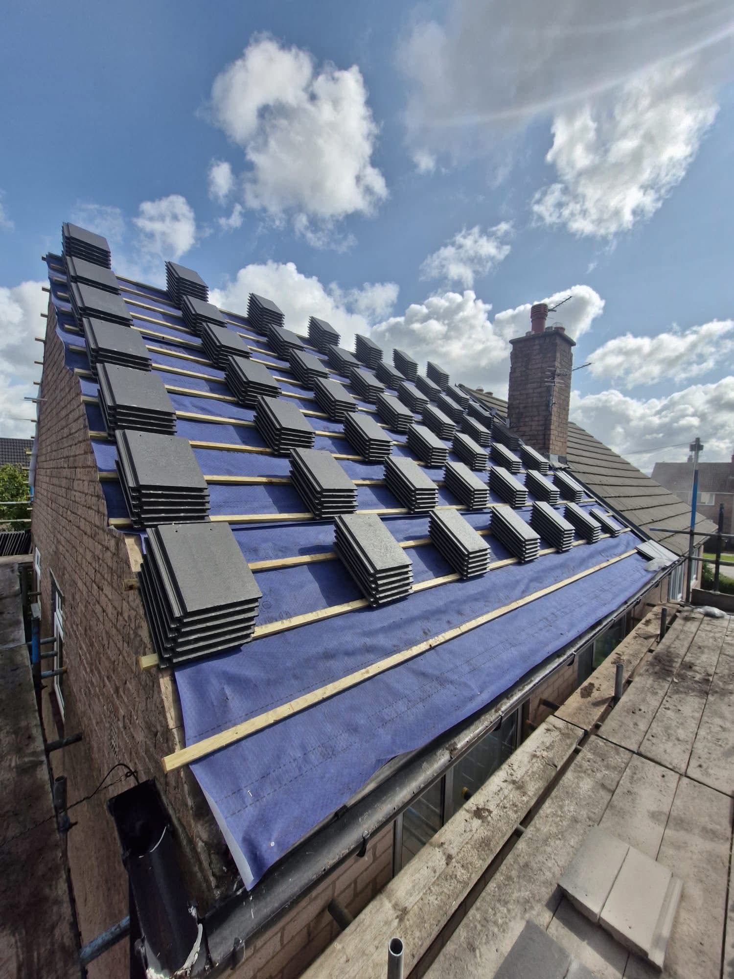 Pitched roof prepared with breathable membrane and stacks of new grey tiles