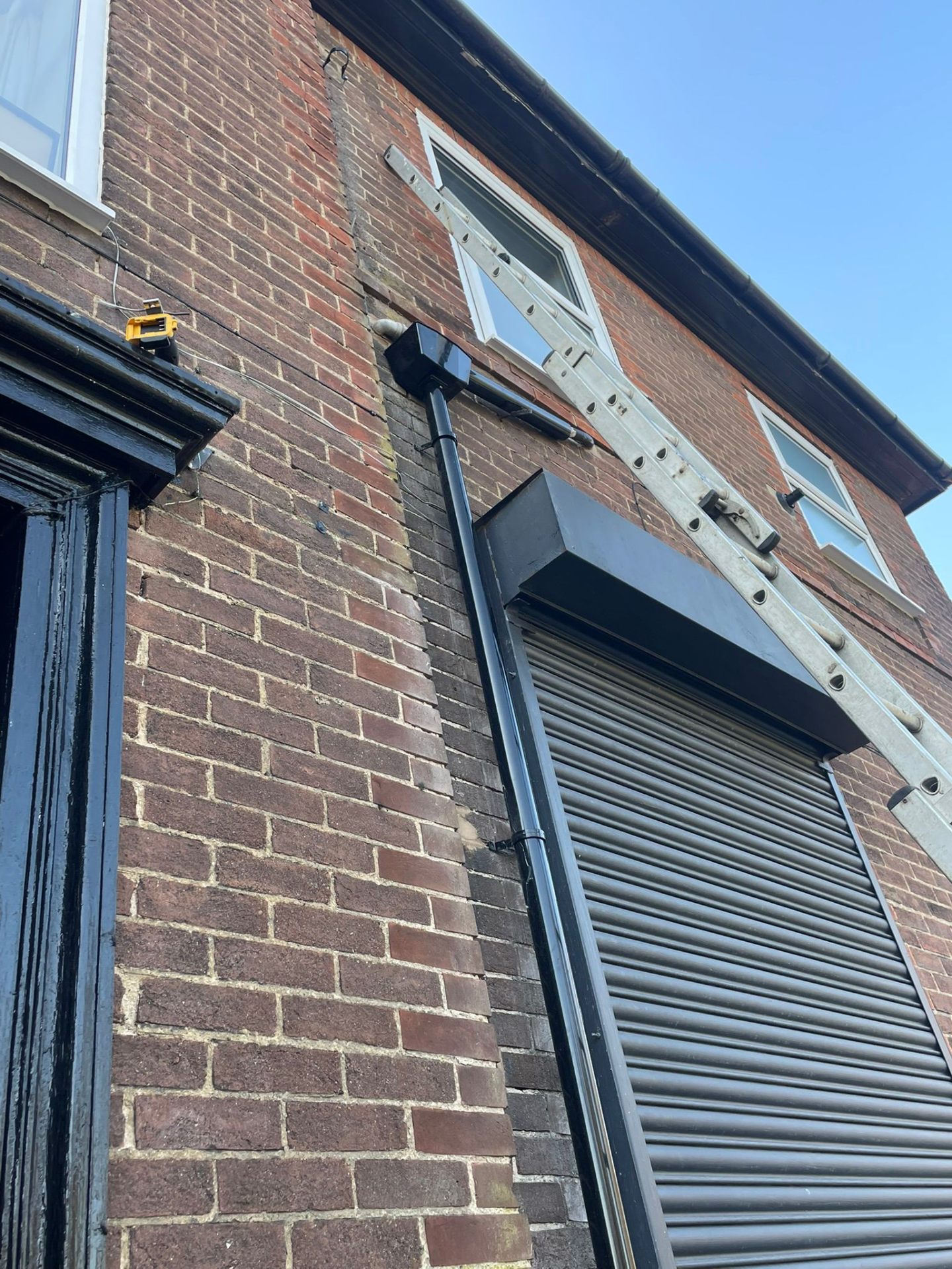Black uPVC downpipe and guttering on a brick property