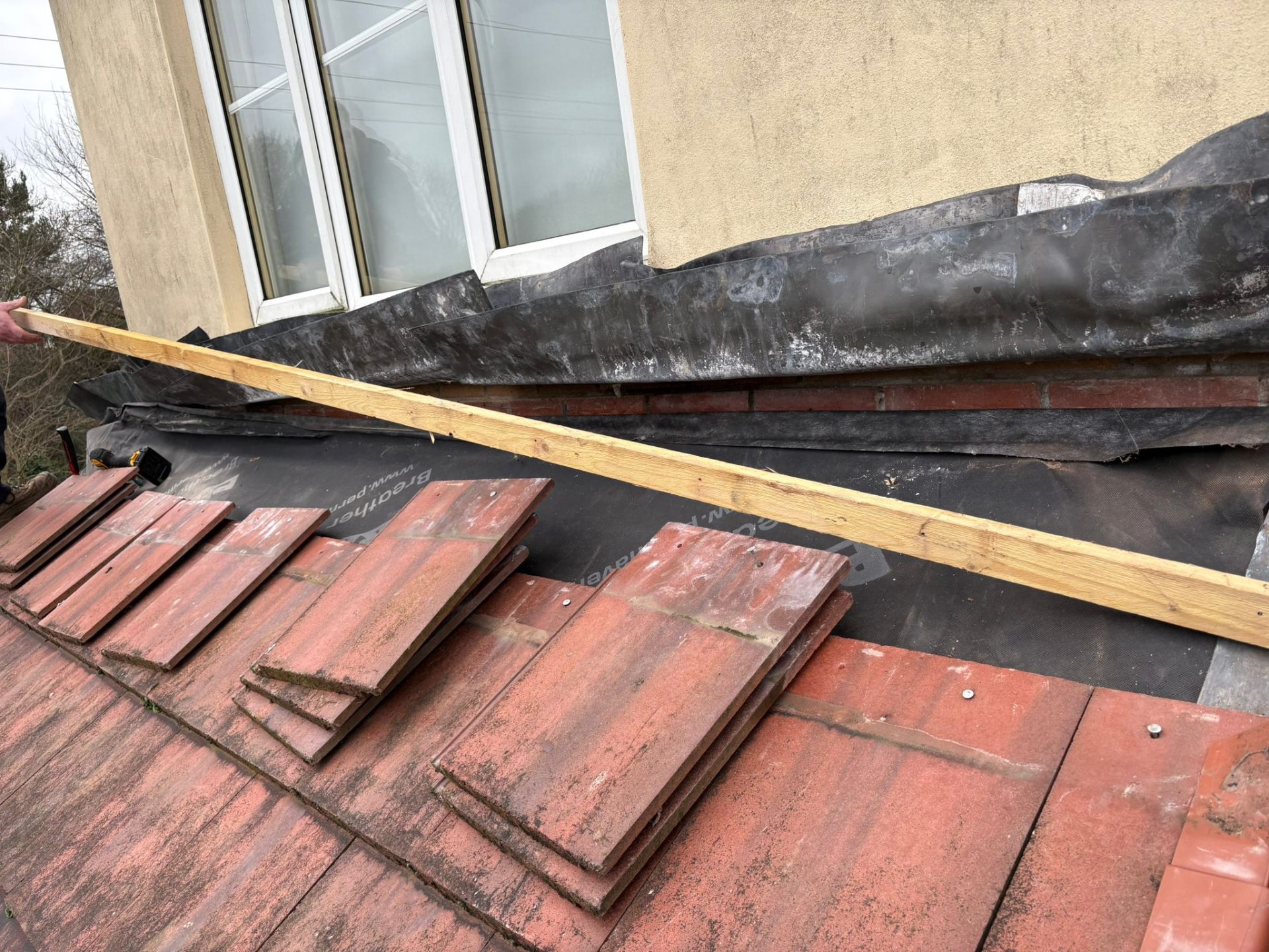 Pitched roof repair in progress showing red tiles and lead flashing detail